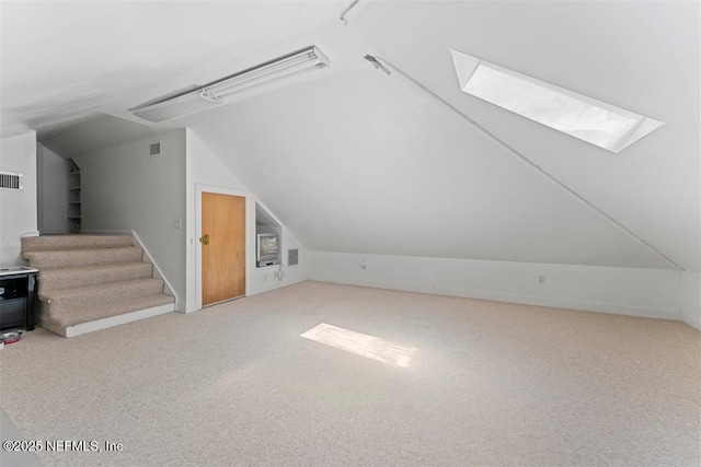 bonus room with lofted ceiling with skylight, visible vents, carpet flooring, and stairway
