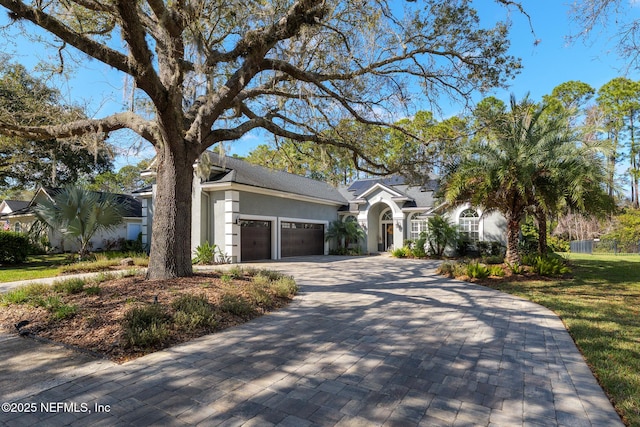 view of front facade with a garage, decorative driveway, and stucco siding