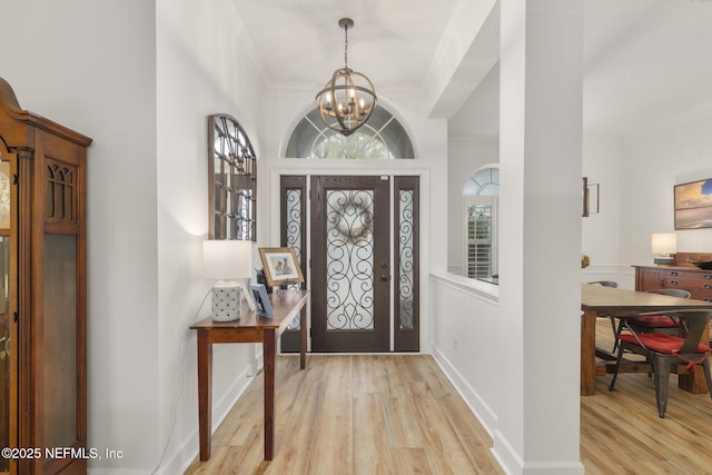 entryway featuring ornamental molding, a chandelier, baseboards, and wood finished floors