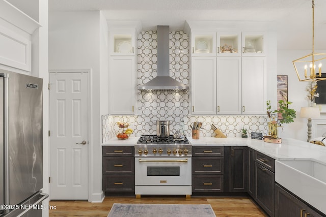 kitchen with stainless steel appliances, white cabinets, and wall chimney exhaust hood