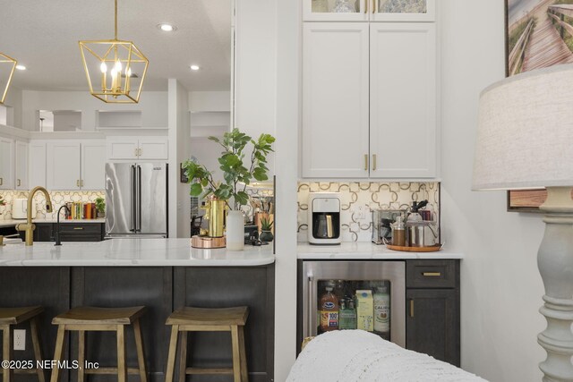 bar featuring beverage cooler, a sink, high end refrigerator, and backsplash