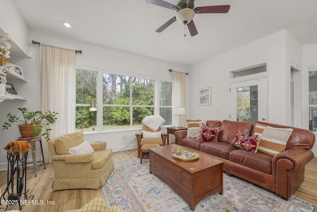 living area featuring ceiling fan, a textured ceiling, baseboards, and wood finished floors