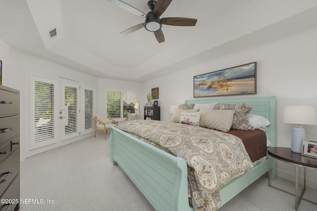 bedroom featuring access to exterior, a tray ceiling, french doors, visible vents, and ceiling fan