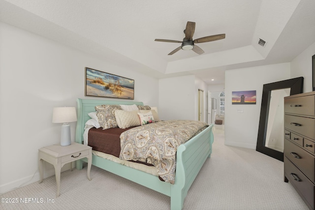 bedroom featuring light carpet, a raised ceiling, visible vents, and baseboards