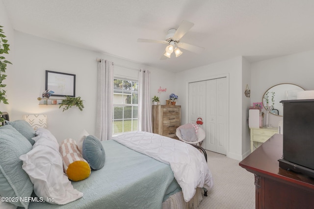 bedroom with light carpet, ceiling fan, a closet, and baseboards