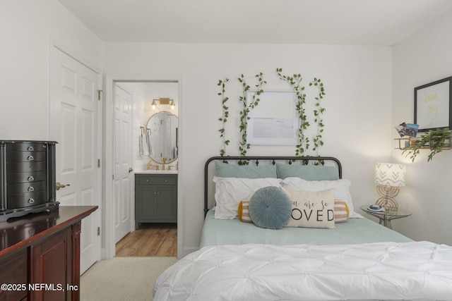 bedroom featuring ensuite bathroom and wood finished floors