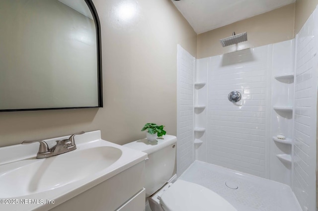 bathroom with vanity, a tile shower, and toilet