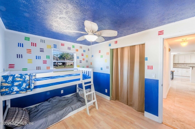 bedroom with ornamental molding, light wood-type flooring, and a textured ceiling