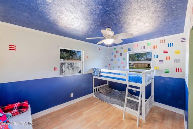 bedroom featuring a textured ceiling, baseboards, and wood finished floors