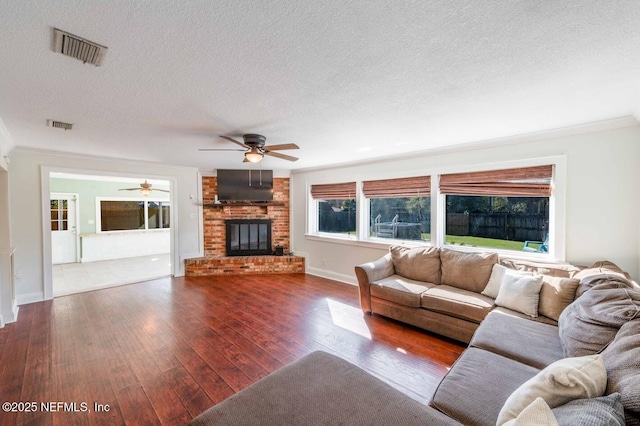 unfurnished living room with a textured ceiling, a brick fireplace, dark wood finished floors, and visible vents