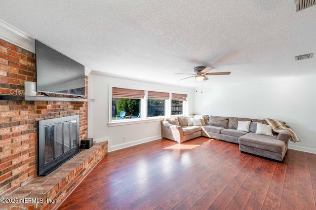 living area with dark wood-type flooring, a brick fireplace, visible vents, and baseboards