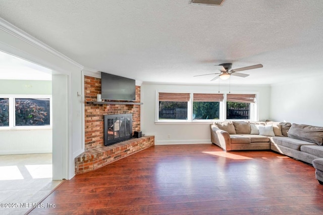 living room with a textured ceiling, a fireplace, wood finished floors, and crown molding