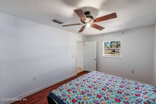 bedroom featuring visible vents, baseboards, dark wood-style floors, ceiling fan, and a textured ceiling