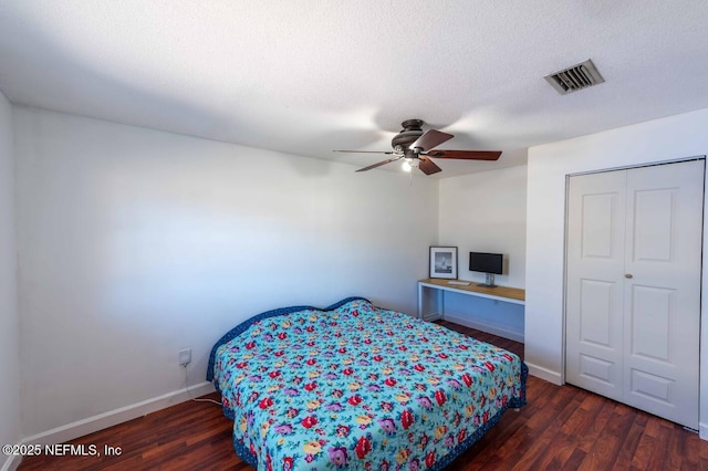 bedroom with baseboards, a textured ceiling, visible vents, and dark wood-type flooring