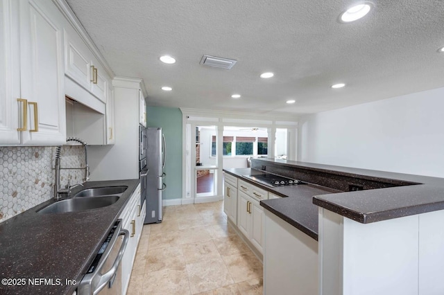 kitchen featuring tasteful backsplash, dark countertops, white cabinetry, a sink, and dishwasher