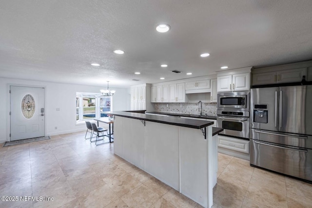 kitchen featuring a breakfast bar area, stainless steel appliances, dark countertops, white cabinets, and a sink