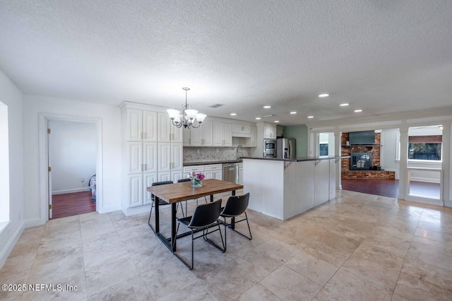 interior space with a textured ceiling, recessed lighting, a fireplace, baseboards, and an inviting chandelier