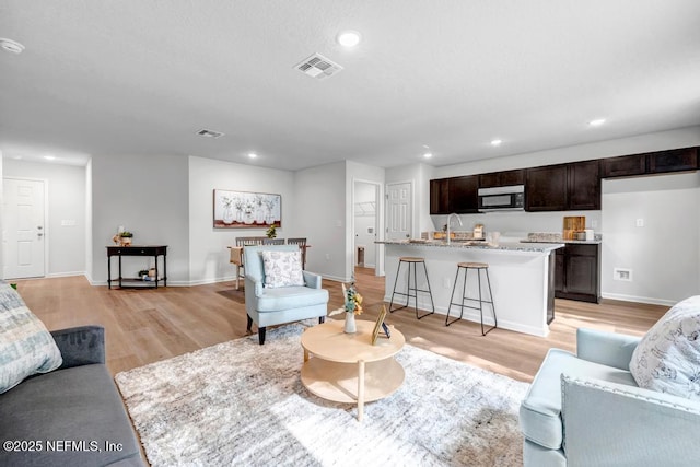 living area featuring light wood-style floors, recessed lighting, and visible vents