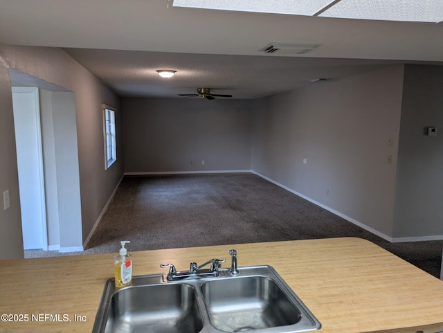 kitchen featuring carpet, open floor plan, visible vents, and a sink