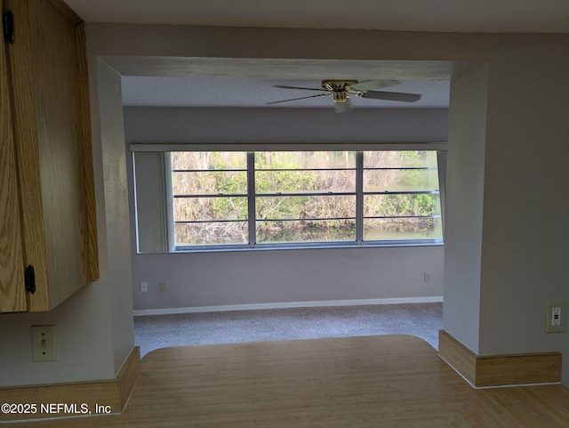 spare room with light carpet, a ceiling fan, and baseboards