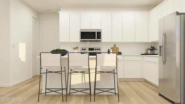 kitchen featuring appliances with stainless steel finishes, light wood-type flooring, white cabinetry, and a kitchen island