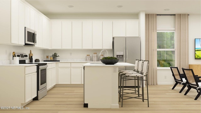 kitchen featuring a center island with sink, stainless steel appliances, light countertops, white cabinets, and a sink