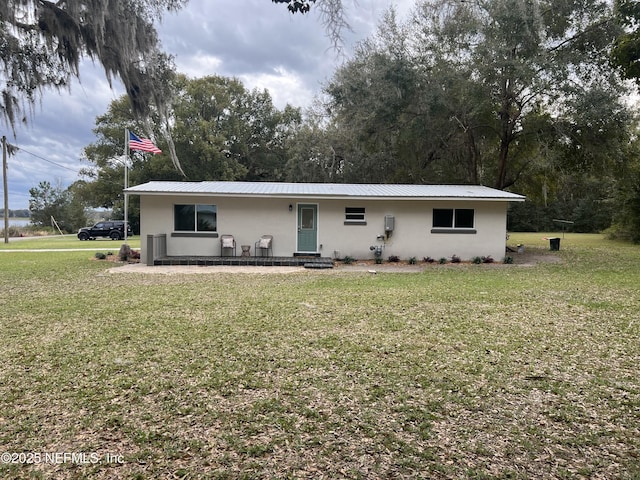 view of front of house with stucco siding, metal roof, and a front yard