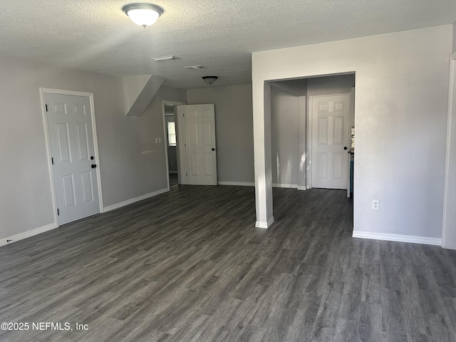 unfurnished living room with dark wood-style floors, a textured ceiling, visible vents, and baseboards