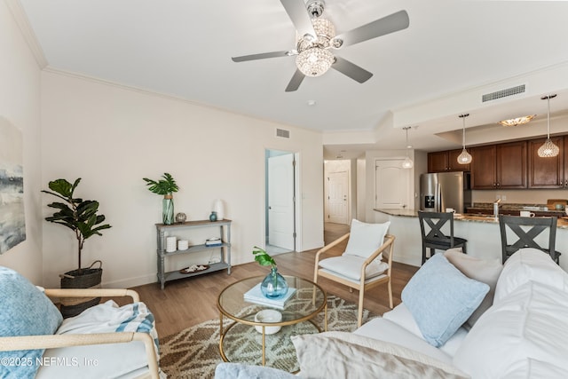 living area featuring ornamental molding, dark wood-style flooring, visible vents, and baseboards