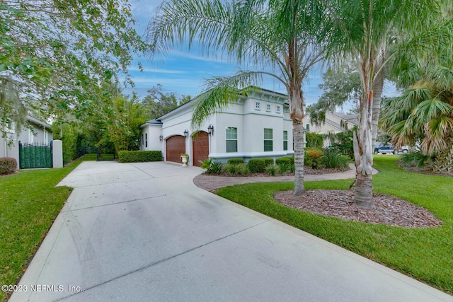 mediterranean / spanish-style home with an attached garage, fence, driveway, stucco siding, and a front lawn