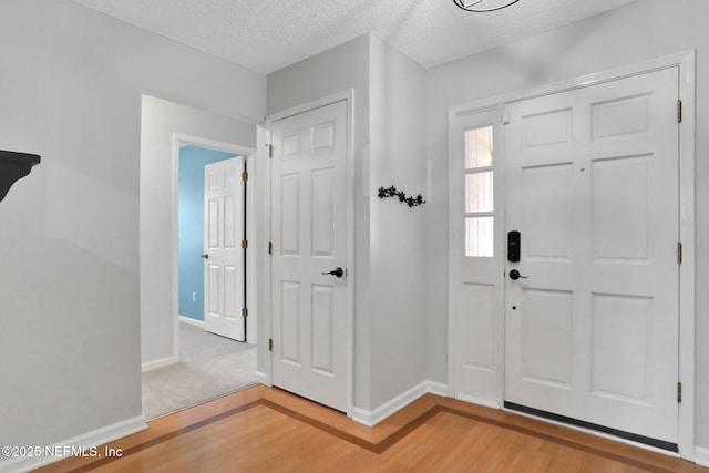 entryway featuring a textured ceiling, baseboards, and wood finished floors