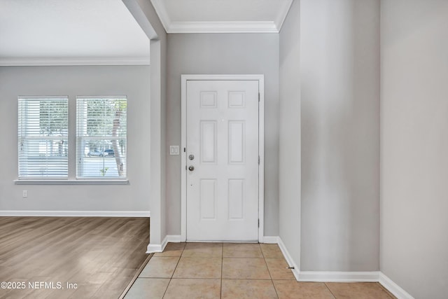 foyer entrance with ornamental molding, baseboards, and light tile patterned floors