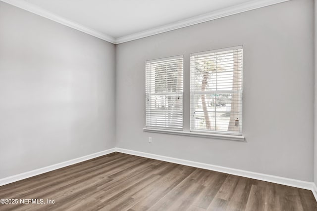 empty room with ornamental molding, baseboards, and wood finished floors