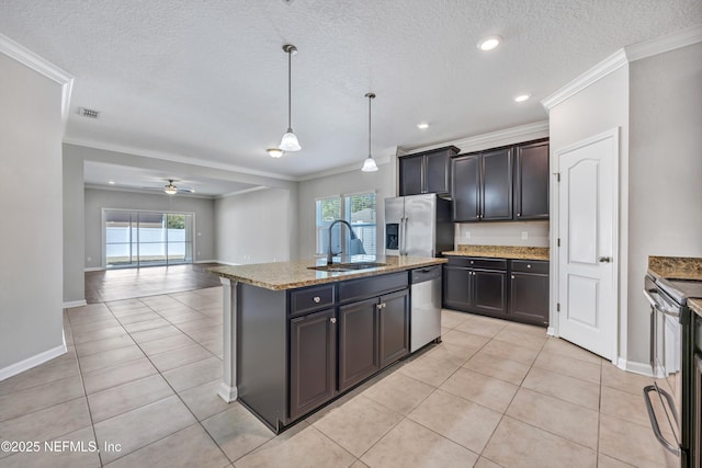 kitchen featuring an island with sink, appliances with stainless steel finishes, open floor plan, decorative light fixtures, and a sink