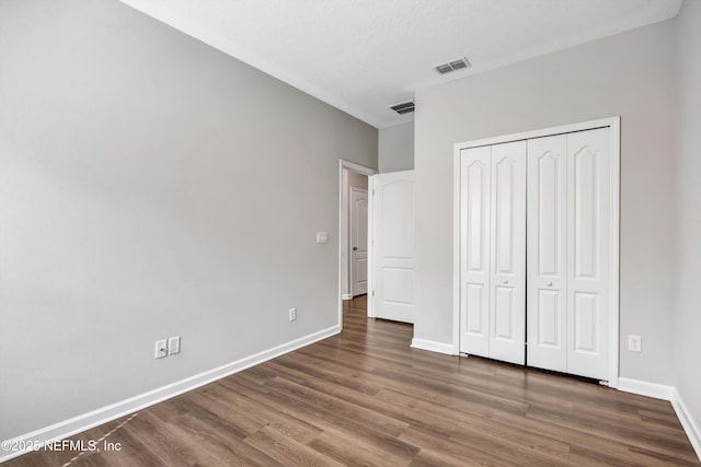 unfurnished bedroom featuring dark wood-style floors, baseboards, and visible vents