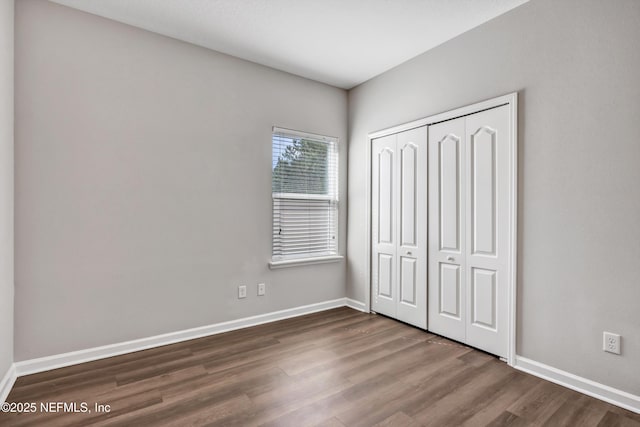 unfurnished bedroom featuring a closet, wood finished floors, and baseboards