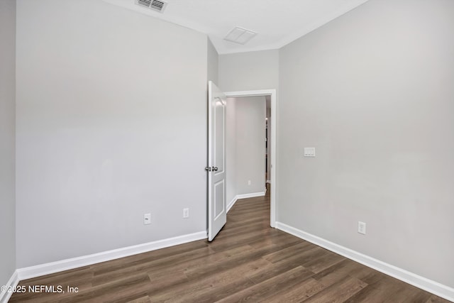 unfurnished room featuring dark wood-style floors, visible vents, and baseboards