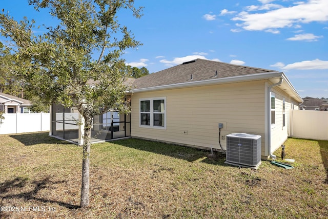 rear view of property with roof with shingles, a lawn, a sunroom, fence, and cooling unit