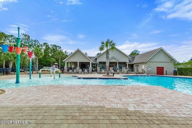 pool with a patio area, fence, and a water play area