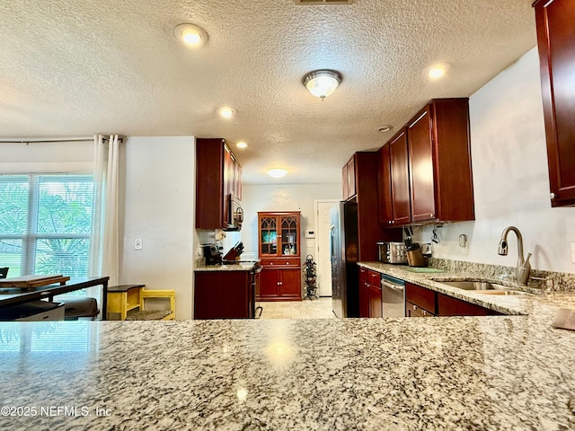 kitchen with stainless steel appliances, reddish brown cabinets, and a sink