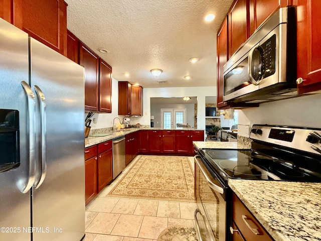 kitchen featuring reddish brown cabinets, light stone counters, and stainless steel appliances