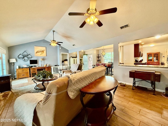 living room featuring lofted ceiling, visible vents, a ceiling fan, light wood-type flooring, and baseboards