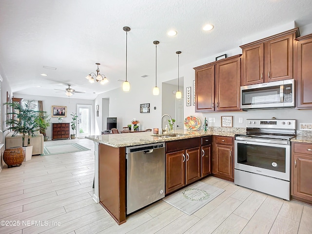 kitchen featuring a peninsula, a sink, vaulted ceiling, appliances with stainless steel finishes, and pendant lighting