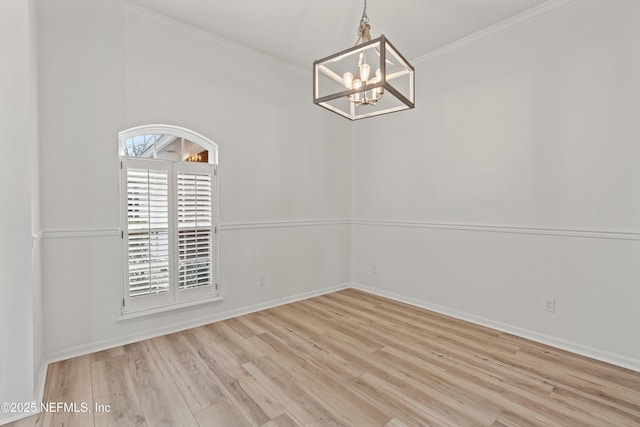 spare room featuring light wood-style floors, baseboards, crown molding, and an inviting chandelier