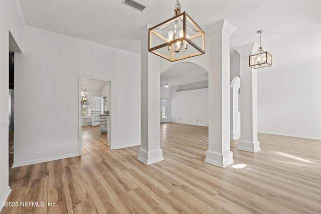 unfurnished dining area featuring visible vents, arched walkways, ornamental molding, light wood-type flooring, and ornate columns