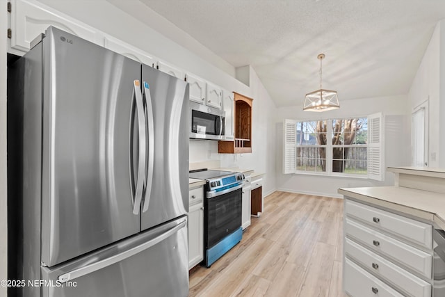 kitchen featuring decorative light fixtures, vaulted ceiling, stainless steel appliances, light countertops, and white cabinetry