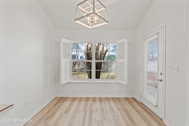 unfurnished dining area featuring light wood-type flooring, vaulted ceiling, and baseboards