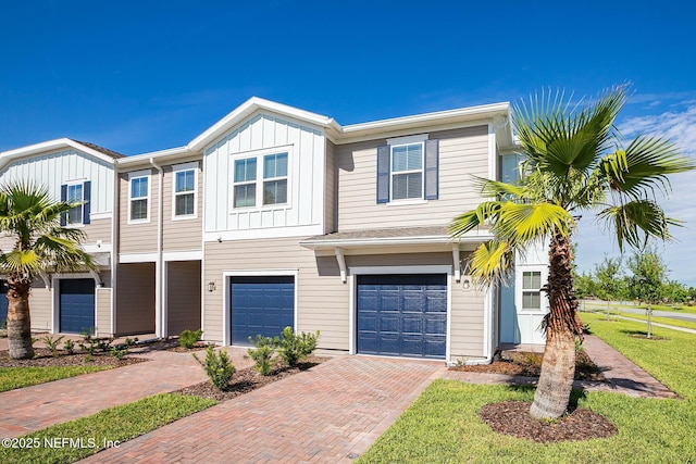 townhome / multi-family property with driveway, a garage, and board and batten siding