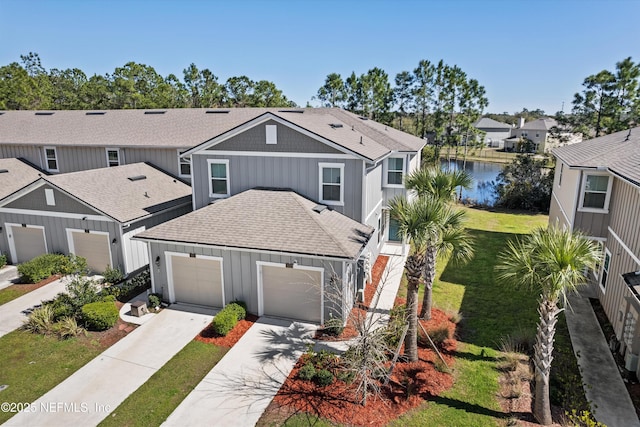 traditional home featuring a garage, a water view, concrete driveway, roof with shingles, and board and batten siding