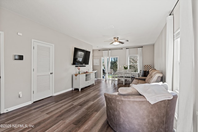 living room with baseboards, dark wood finished floors, and a ceiling fan